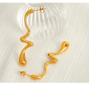 Close-up of golden irregular wavy curve earrings on soft white textured fabric