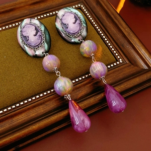 Detailed view of vintage resin portrait earrings with purple beads and teardrop pendants