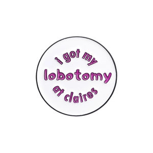 Round white enamel pin with purple 'i got my lobotomy at claires' text on white background