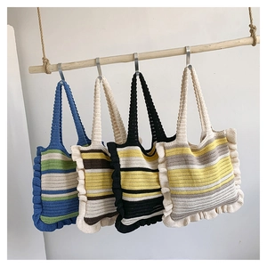 Detail of four handmade knitted tote bags with ruffles and colorful stripes on wood