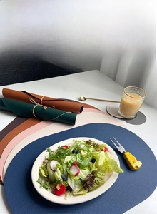 Detail showing various colors of oval PU leather placemats with soft and flexible texture