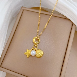 Close-up of golden starfish and pearl pendant displayed on a beige jewelry box