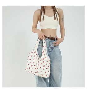 Detail of large-capacity white tote bag featuring red strawberry print and corduroy texture