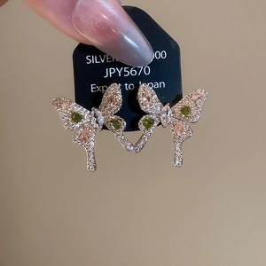 Macro shot of rose gold butterfly earrings featuring green and pink marquise stones