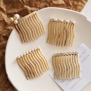Set of four gold hair combs with pearls and rhinestones on a decorative ceramic plate