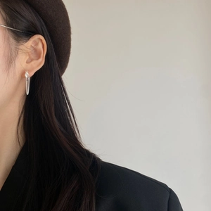 Close-up of a stylish silver long chain drop earring worn on a model with a beret