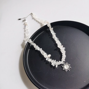 Detailed shot of irregular clear quartz stone necklace with silver sun pendant charm