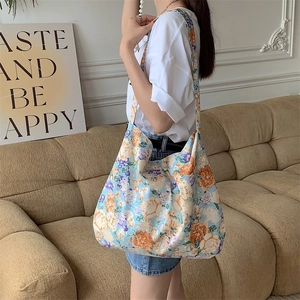Close-up of a floral print canvas tote bag in light blue with orange and white flowers