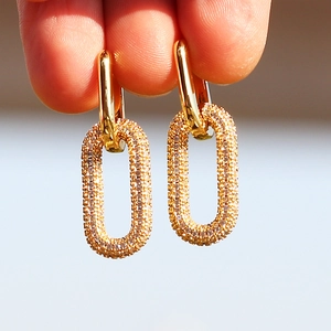 Macro shot of gold-plated U-shaped earrings with pavé zircon oval link details