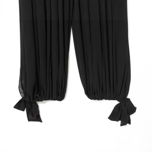 Combinaison noire à la mode avec poignets plissés et nœuds décoratifs aux chevilles
