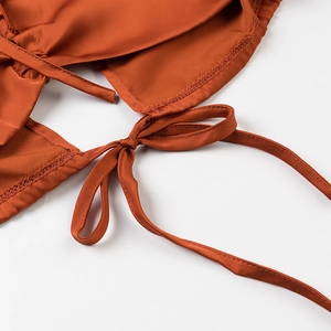 Détail de la conception du nœud au dos sur un crop top orange ajouré