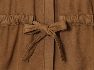 Détail du pantalon en daim marron foncé avec un nœud de ceinture élégant à la taille