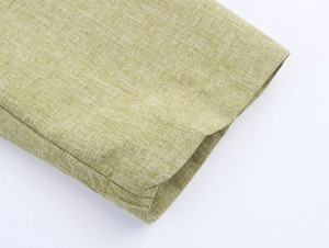 Detailed close-up of light green linen fabric showing refined texture and stitching