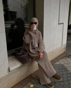 Detail of light brown knitted two-piece set featuring half-zip top and wide-leg trousers