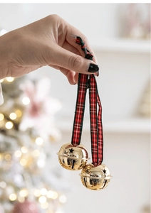 Macro view of golden Christmas bells with red green plaid ribbon on a warm festive tree
