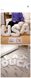 Detail of plush alphabet letter pillows in soft white sherpa fabric on a cozy sofa