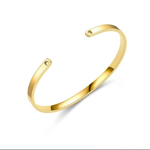 Detail view of a gold C-shaped titanium steel bracelet with heart cutouts at the ends.