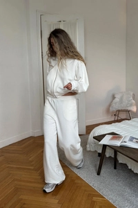 Detail view of white loungewear set with zip-up hoodie and wide-leg joggers in home setting