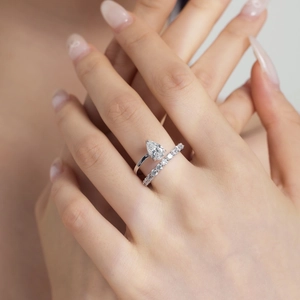 Close-up of a pear-cut diamond ring set and eternity band worn on a woman's finger