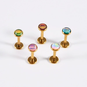 Five gold stainless steel labret studs with rainbow iridescent round gemstones on white background