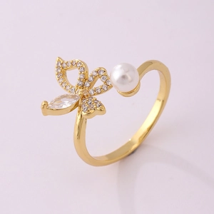 Detailed macro view of 18K gold-plated bow ring with cubic zirconia and white pearl