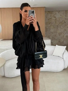 Detail of ruffled black chiffon dress with lantern sleeves and layered hem finish