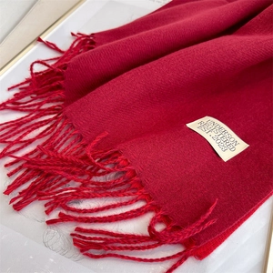 Detailed close-up of a red cashmere-feel scarf featuring fringe tassels and an Underson label
