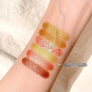 Swatch di 6 ombretti con texture glitterate e perlate mostrate sulla pelle del braccio