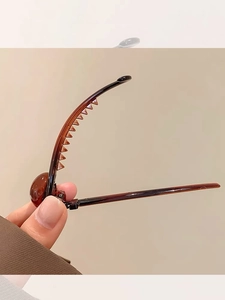 Detail of amber translucent hair clip with a minimalist twisted design and comb teeth