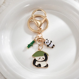 Close-up of golden metal panda keychain with green bamboo and enamel charms detail