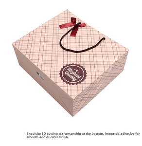 Detailed view of pink plaid gift bag with red bow and highest quality label