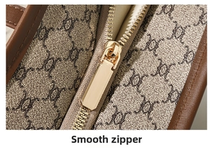 Close-up of smooth gold zipper and vintage monogram pattern on a large tote bag
