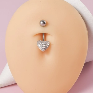 Close-up of silver belly button ring featuring a dangling heart-shaped zircon pendant