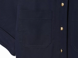 Détail d'une robe chemise bleu marine avec boutons dorés et surpiqûres de poche précises