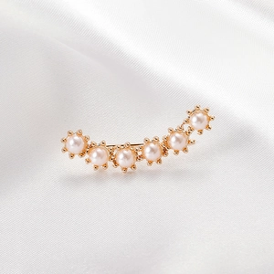 Close-up of gold-plated curved ear cuff decorated with six sunburst pearl clusters