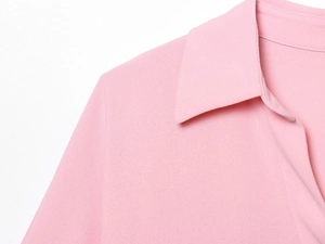 Détail du revers et de l'épaule de la blouse rose avec tissu texturé sur fond blanc