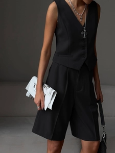 Detailed close-up of a black V-neck buttoned vest and straight-leg tailored suit shorts