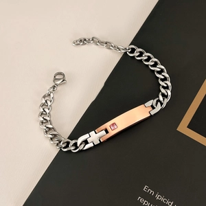 Macro shot of silver and rose gold Cuban chain bracelet with pink gemstone on rectangular bar