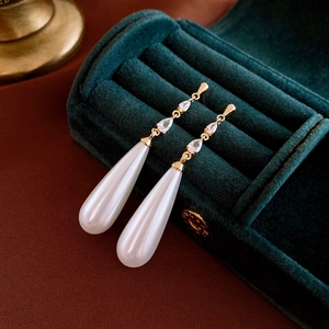 Macro shot of vintage pearl earrings on a velvet box showing elegant water drop design