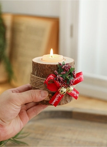 Close-up of a rustic wooden Christmas candle holder with red ribbon and holly berries