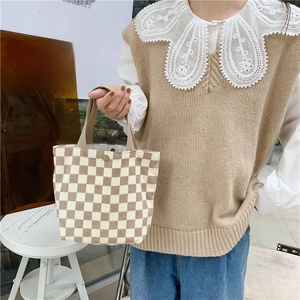 Detail of checkered corduroy tote bag with metal snap button and sturdy woven handle