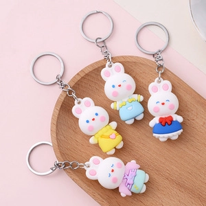 Close-up of colorful cartoon rabbit keychains in blue pink and yellow on a wooden tray