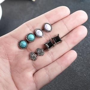 Set of four vintage turquoise and hamsa hand stud earrings held on a hand for display