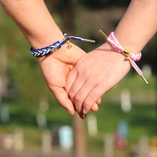 Close-up of magnetic couples bracelets in blue and pink woven rope with gold charms