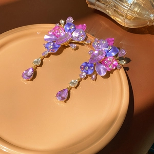 Detailed view of floral drop earrings with purple crystals on a ceramic display dish