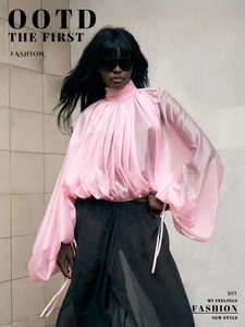 Detail of pink high-neck pleated blouse with sheer lantern sleeves and glossy texture