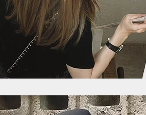 Detailed close-up of a black crossbody bag with a polished metal chain strap and leather