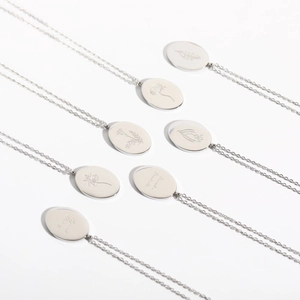 Detailed macro view of silver stainless steel necklaces featuring engraved floral oval pendants