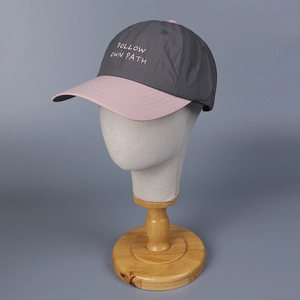 Detail of grey and pink baseball cap with Follow Own Path embroidery and mesh texture