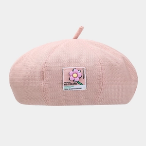 Detailed view of pink knitted beret featuring colorful HS-TREAND floral patch